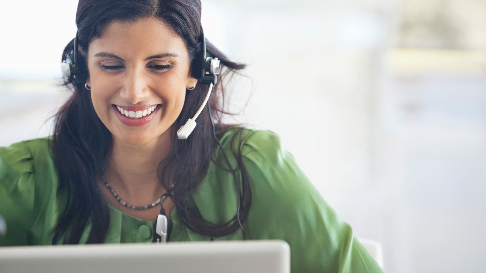 Woman wearing headset looking at laptop.