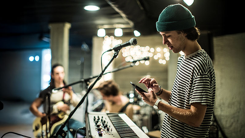 Musician using smartphone during band rehearsal.